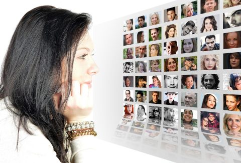A woman is sitting at a computer looking a pictures of people