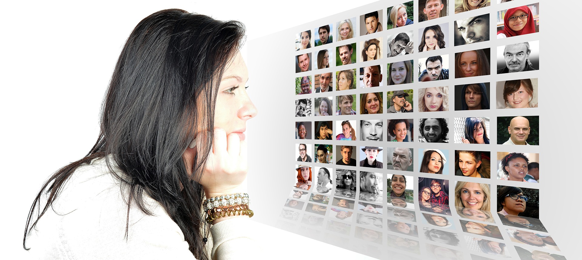 A woman is sitting at a computer looking a pictures of people