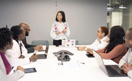 A group of people are siting around a conference table and talking