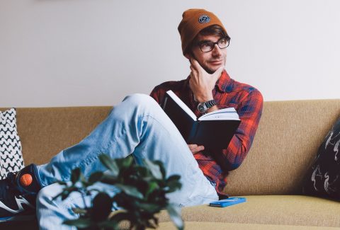 A man is sitting with a book, and pondering a thought