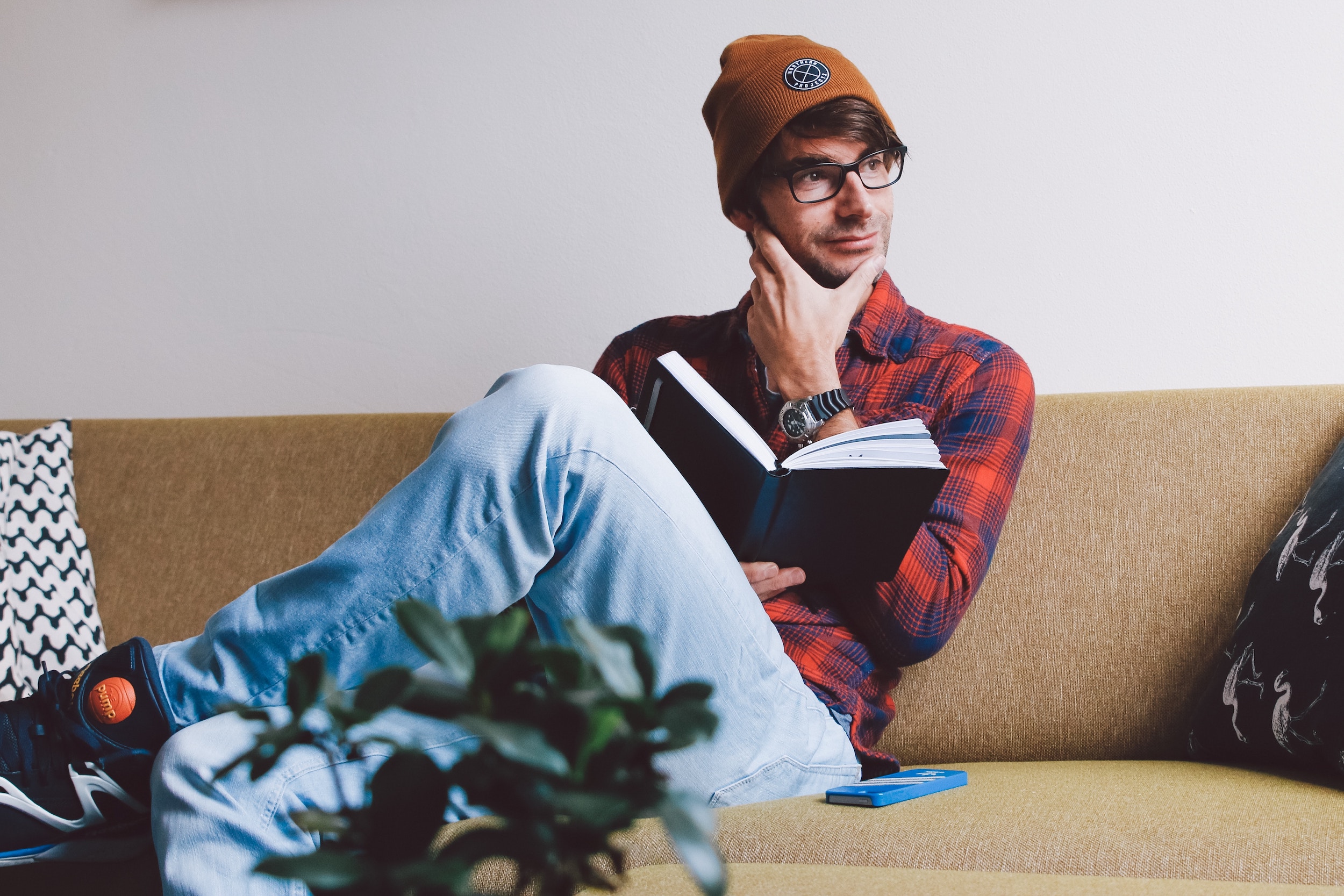 A man is sitting with a book, and pondering a thought