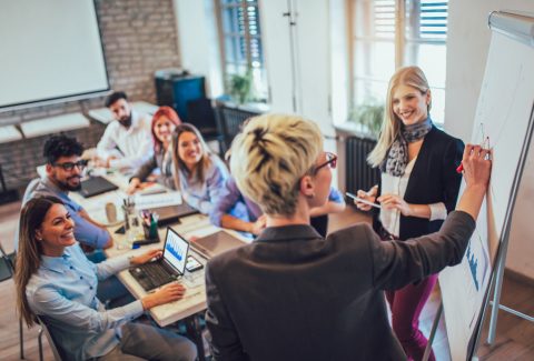 A group of men and woman are sitting around a conference table talking