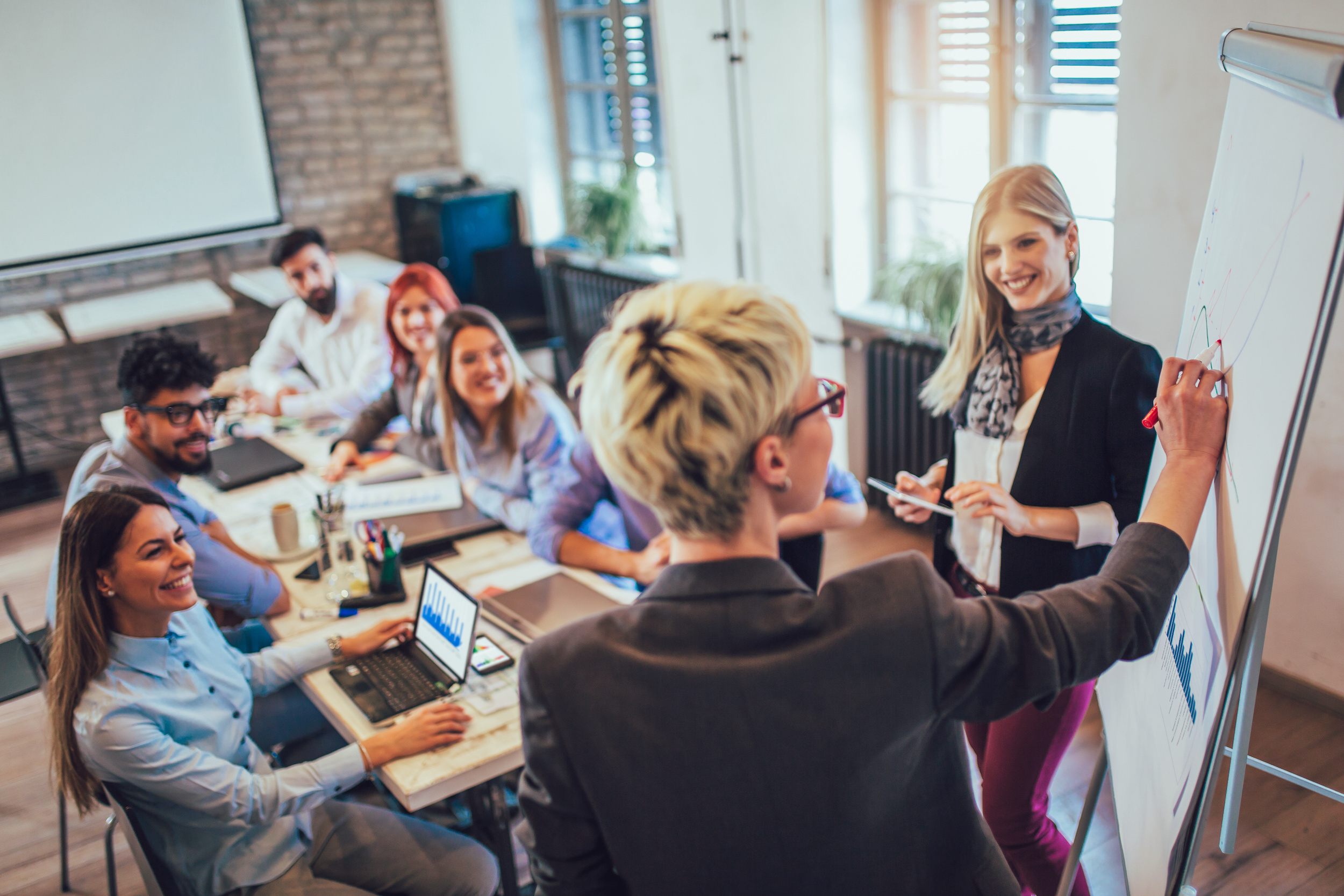 A group of men and woman are sitting around a conference table talking