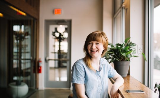 A woman is sitting and looks to be talking to someone