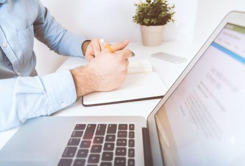 A man is sitting next to a laptop computer