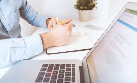 A man is sitting next to a laptop computer