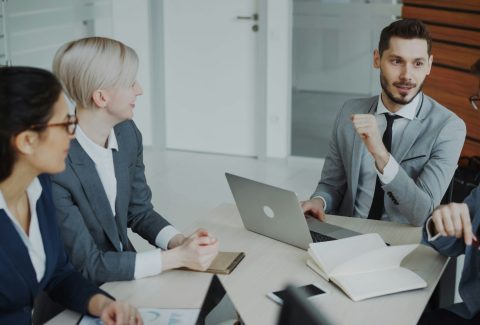 A group of business men and woman are sitting and talking
