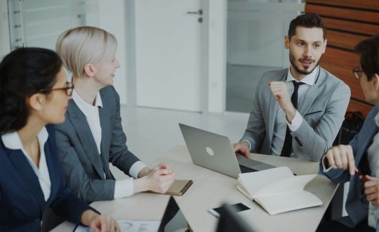 A group of business men and woman are sitting and talking