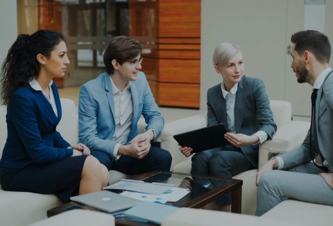 A group of business men and woman are sitting and talking