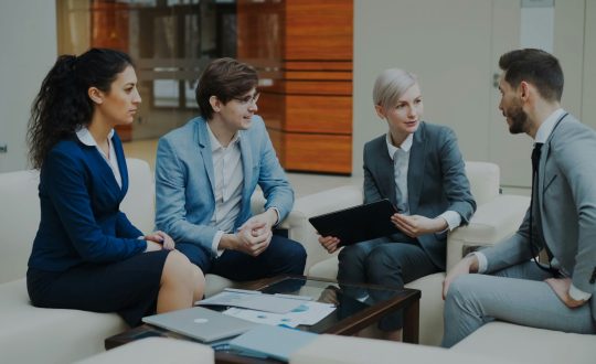 A group of business men and woman are sitting and talking