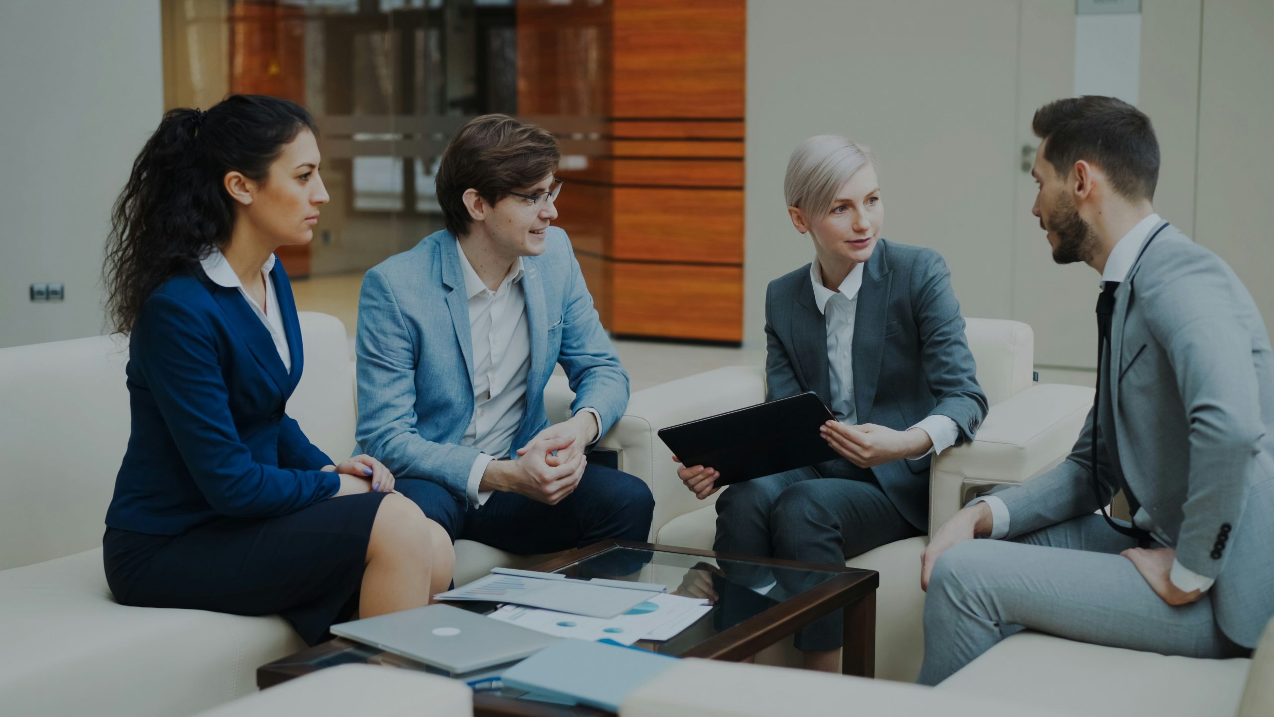 A group of business men and woman are sitting and talking