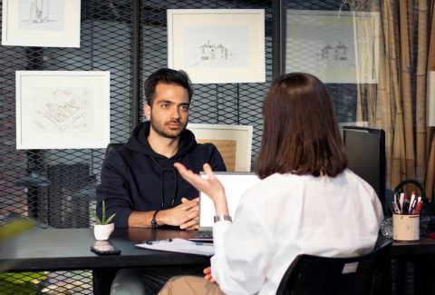 A man and a woman are sitting in an office and talking