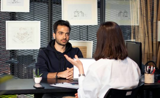 A man and a woman are sitting in an office and talking