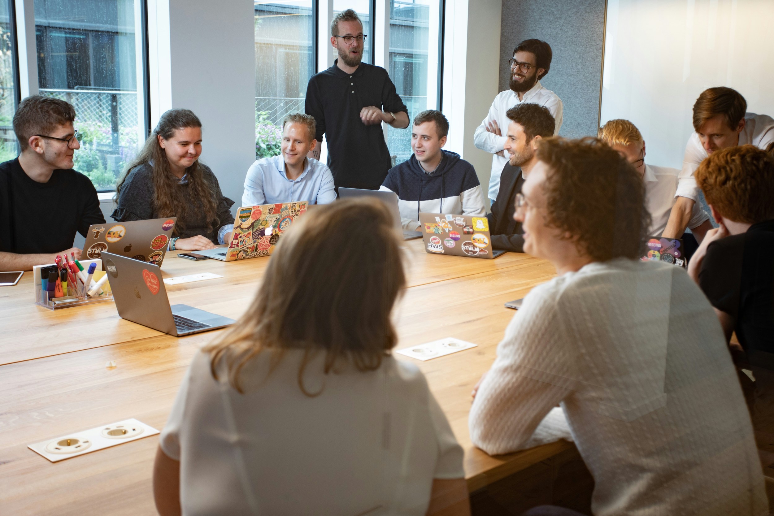 A large group, of men and woman are sitting in a conference room or classroom talking