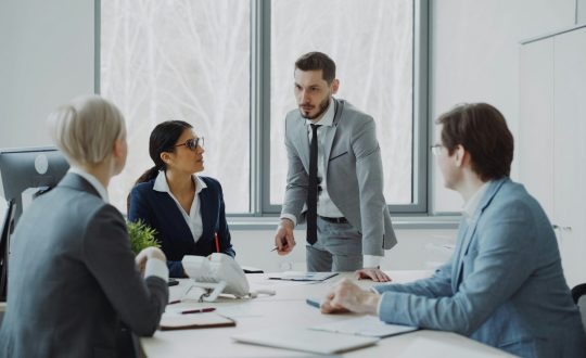 A group of men and woman are in a conference room and talking